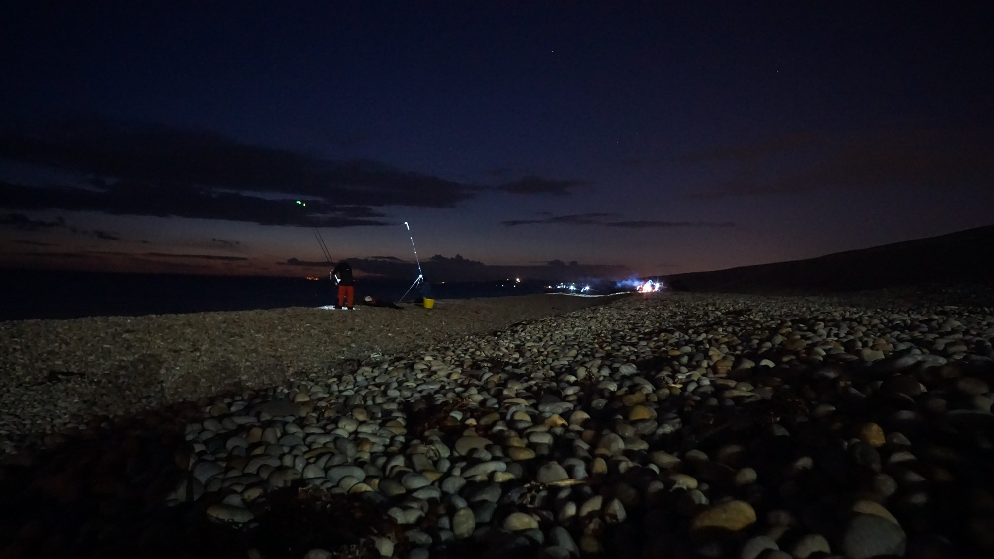 Ein Angler am Chesil Beach bei Nacht.